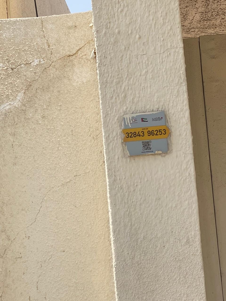 Dubai Makani location plate reading 32843 96253 fixed to the site boundary wall