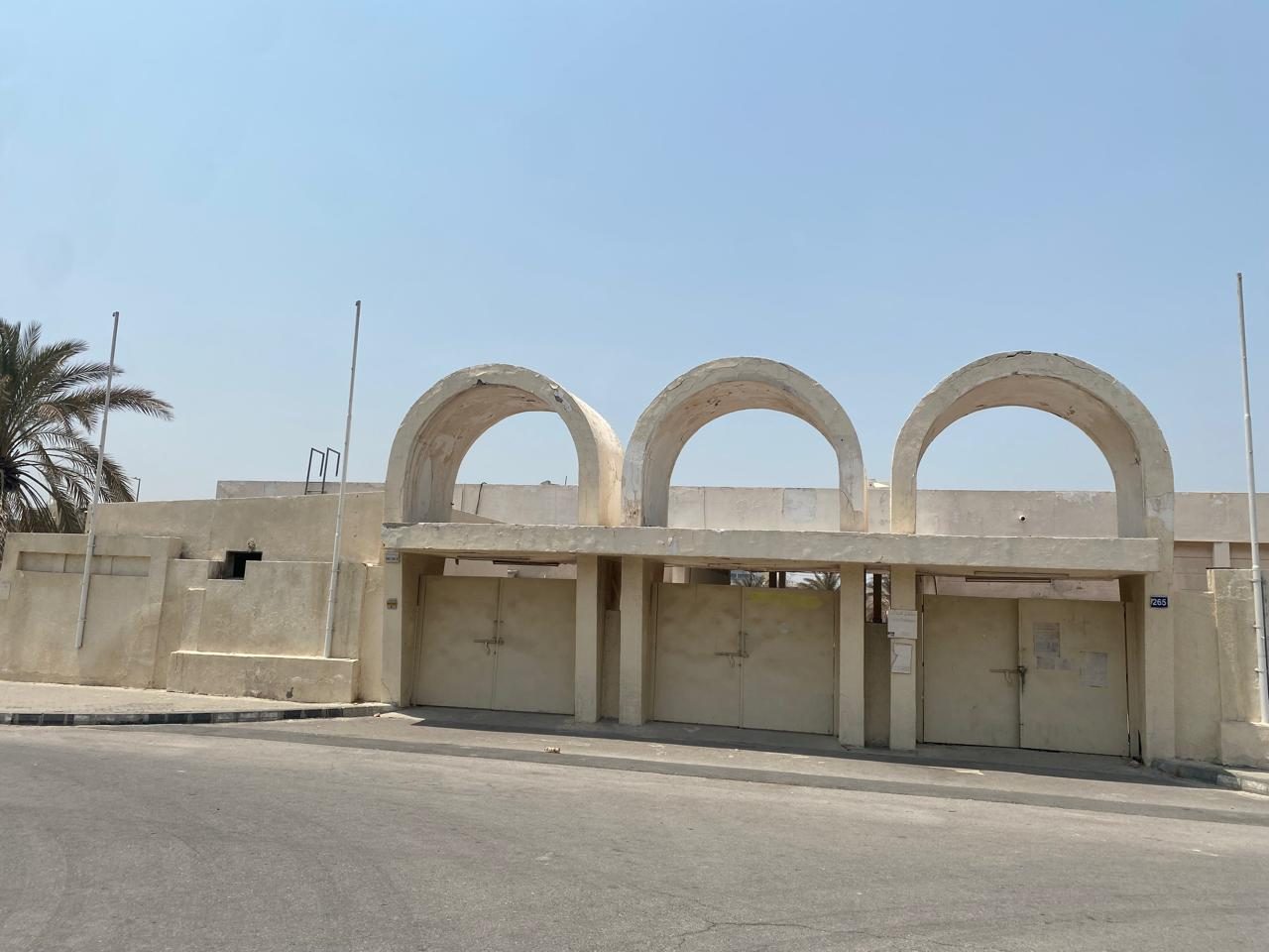 Existing boundary wall with three arched openings and gated vehicle access